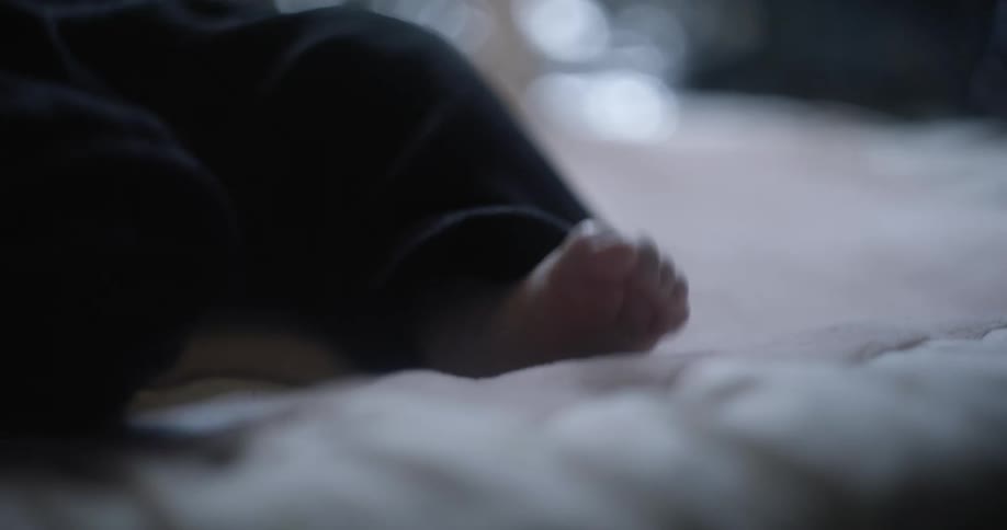 Bare feet of a baby kicking around laying in bed at home