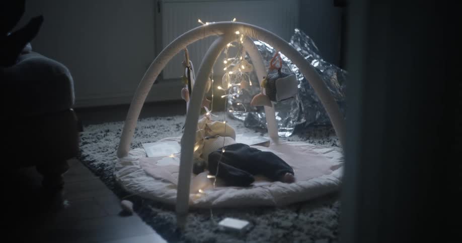 A baby in a room laying on the floor playing with a mobile