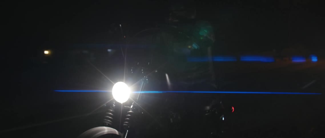 Motorcyclists riding on a paved road in the dark