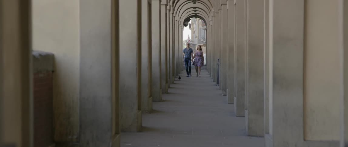 Two people walk through building pillars