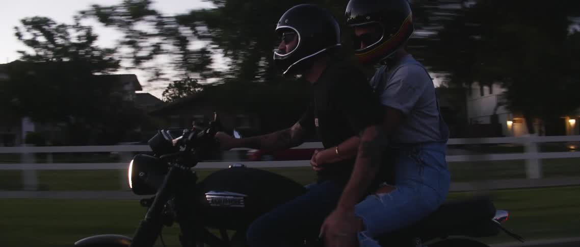 Two people riding a motorcycle together in a neighborhood