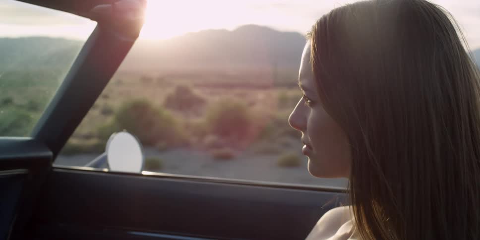Young woman riding through the countryside in a convertible