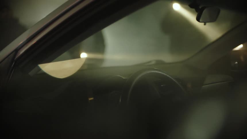 A group of people that are shining flashlights into a car