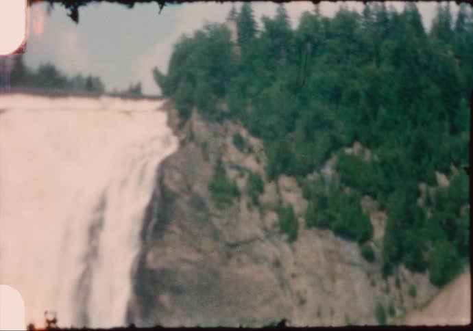 A large waterfall flowing over a cliff in nature on a summer day