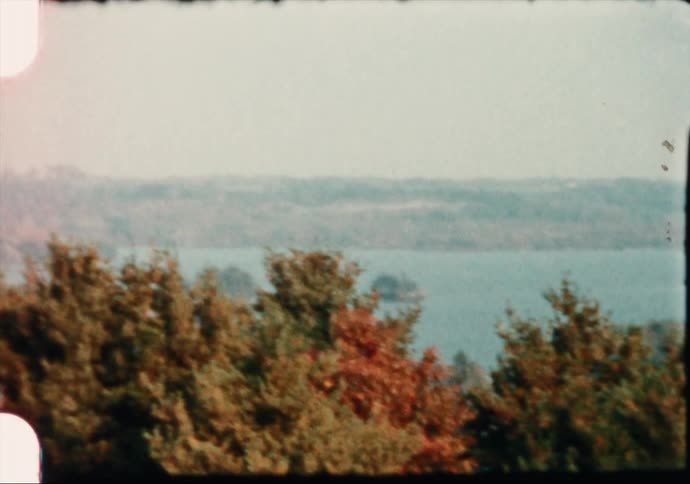 A lake sits in the middle of a forest in autumn