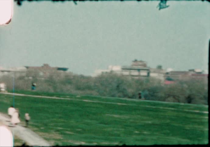 Waving american flags waving in the wind near a monument caught on vintage film