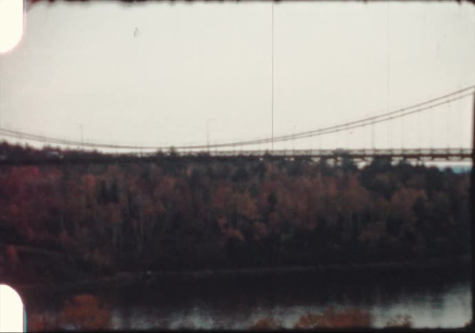 Vehicles driving on a suspension bridge over the river at evening