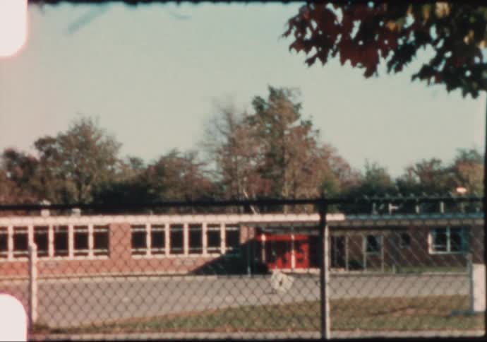 An 8mm film camera pans the grounds of a school yard in the 1960's