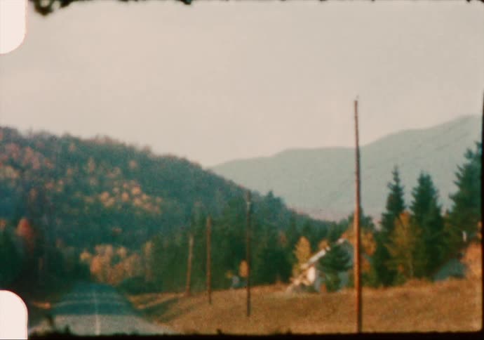 A country home along a long road rests at the feet of mountains in the fall
