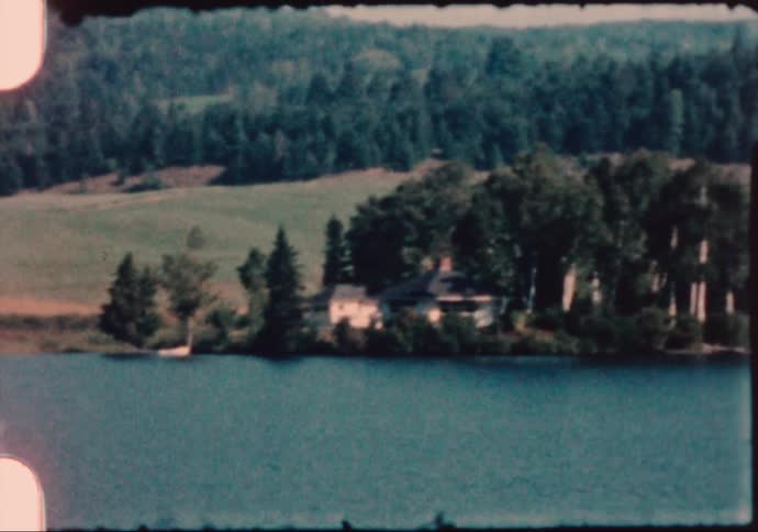 Vintage footage of houses on a lake in the mountains
