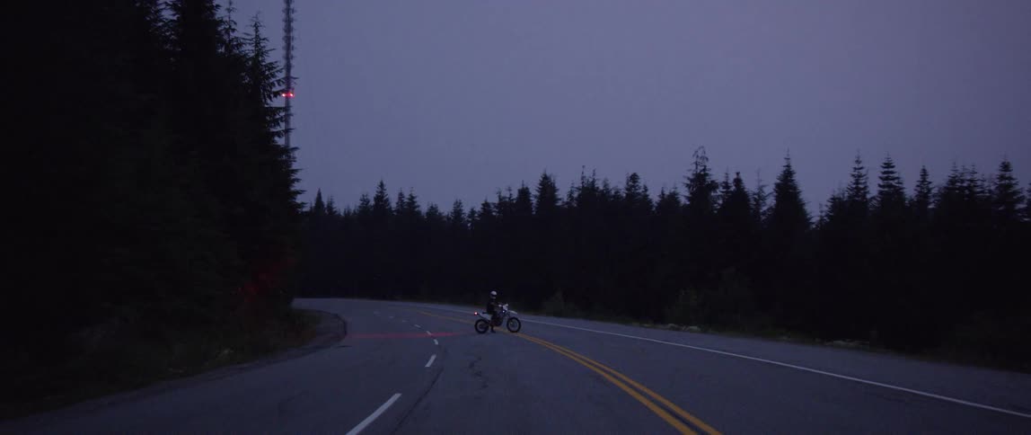 Motorcycle driving on a two way road in the mountains stops in the middle lane