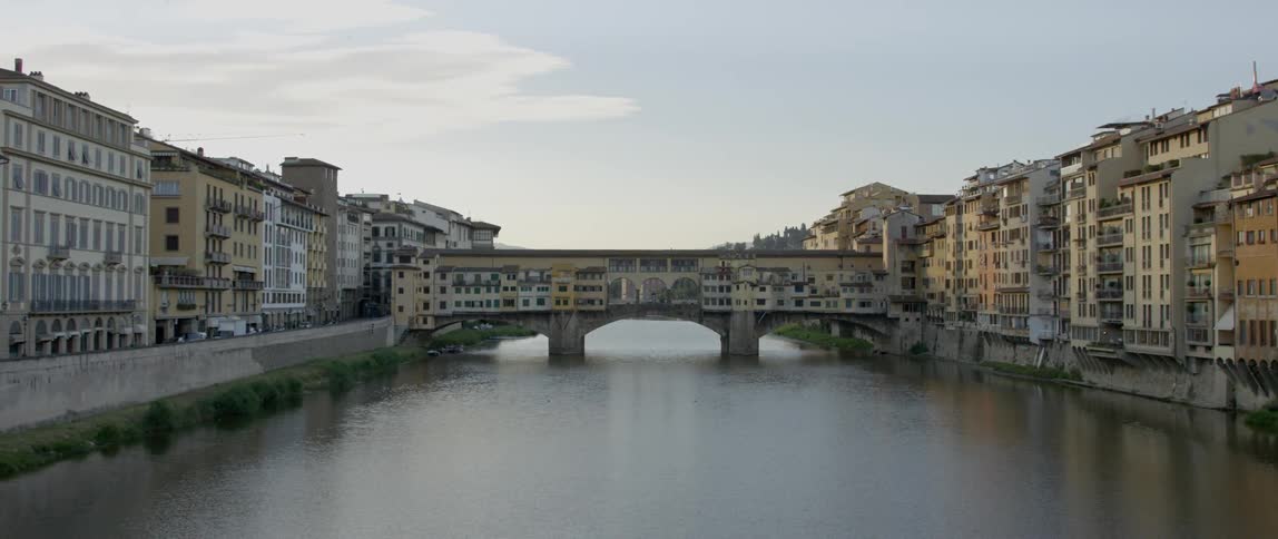 A bridge has a building built on it and is gaping a body of water
