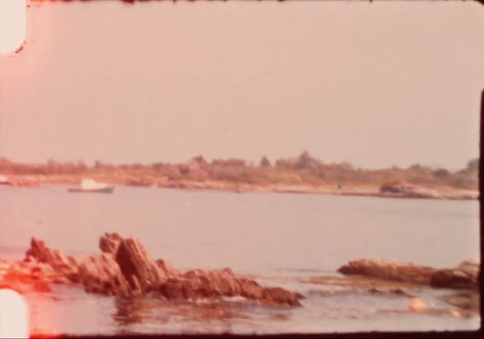 A small house in front of a river at daytime caught on yellowing film
