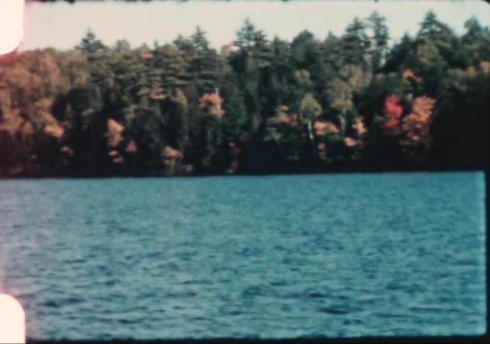 Autumn colors begin to show along a shoreline in 1960's New England