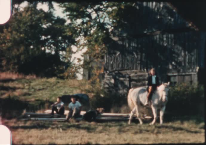 Family riding horses on a farm in the 1950's