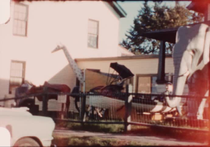 The setting sun flares as a vintage 8mm camera pans across a small roadside wax museum