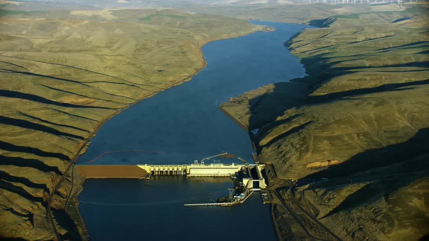 Wide aerial shot of Lowe Monumental Dam on the Lower Snake River in Eastern Washington showing the vastness of the river canyon