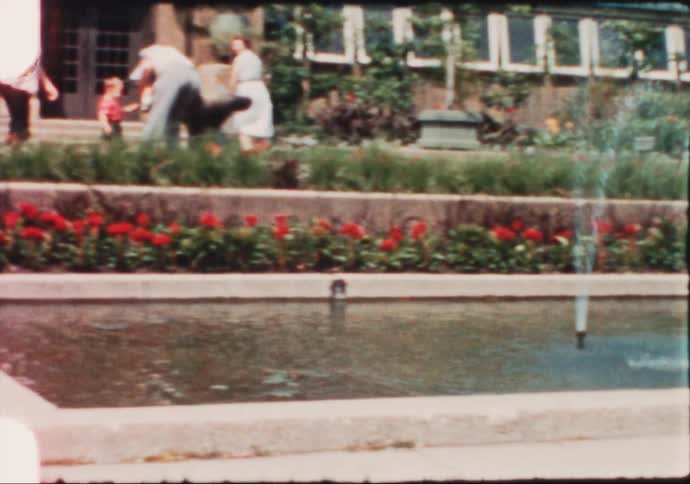 Family walking in the gardens of a pakr near a fountain