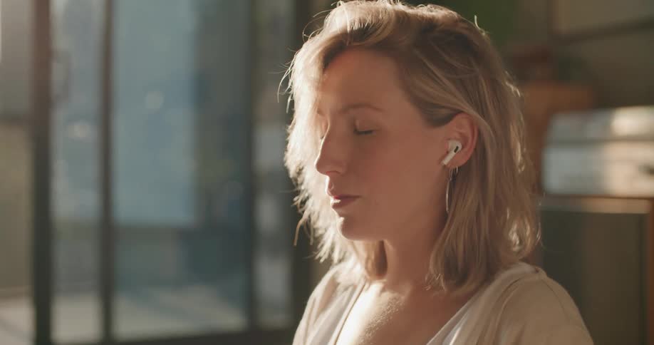 Blonde pregnant woman with earphones sits on the floor and listens to music