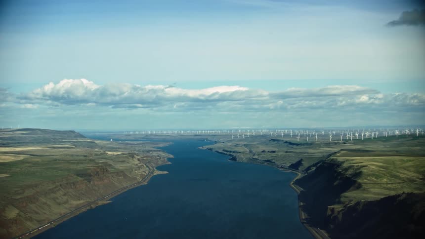 Windfarms are spinning farm above the wide expanse of the Columbia River Gorge on the border of Oregon and Washington in the vast aerial shot