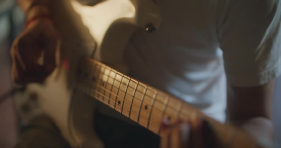 Man plays white and gold colored electric guitar