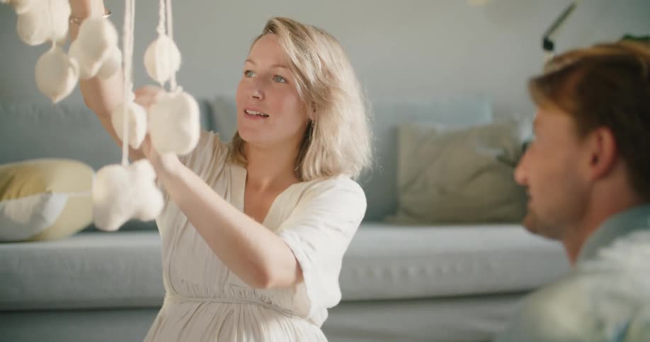 Young couple sitting in the living room at home looking at baby toys