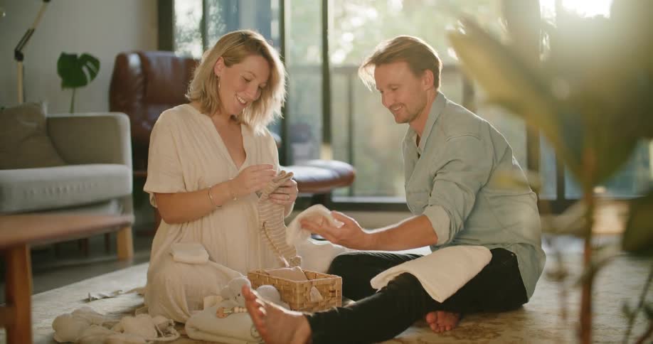A couple looking at baby clothes in the lounge room