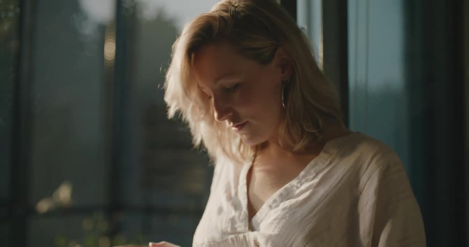 A woman is holding a hot drink in her home