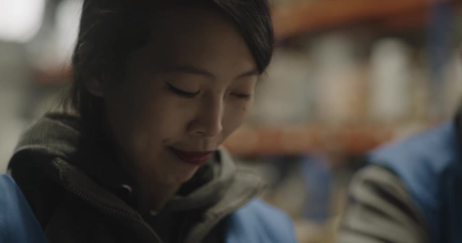 A female smiling while talking to a coworker in a warehouse