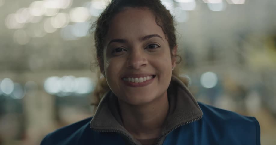 A woman looks up and smiles with lights glowing behind her