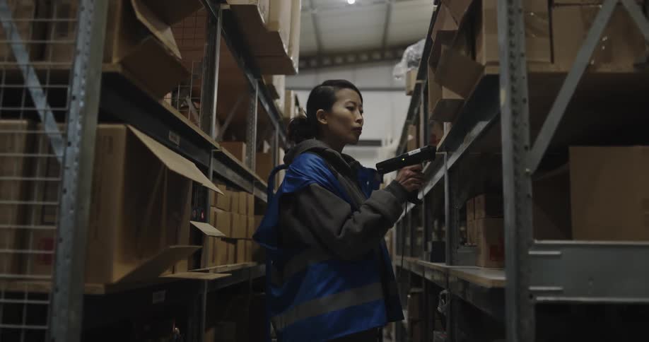 A woman is scanning packages in a warehouse