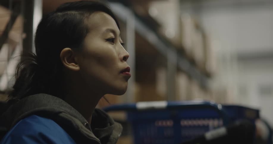 A woman scanning boxes in a warehouse with shelves in the background