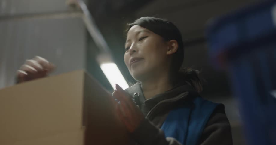 A woman is working in a warehouse and packaging boxes