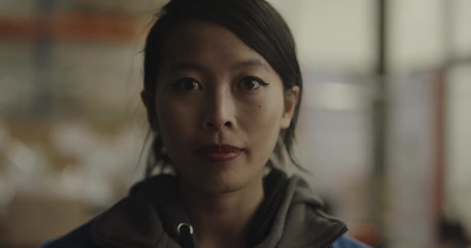 Female warehouse worker faces the camera with eye contact in the warehouse