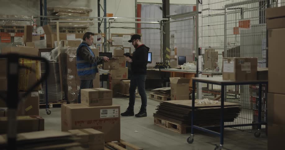 Man working on a warehouse delivers a box to a client