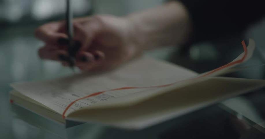 A person is writing in a book during the day