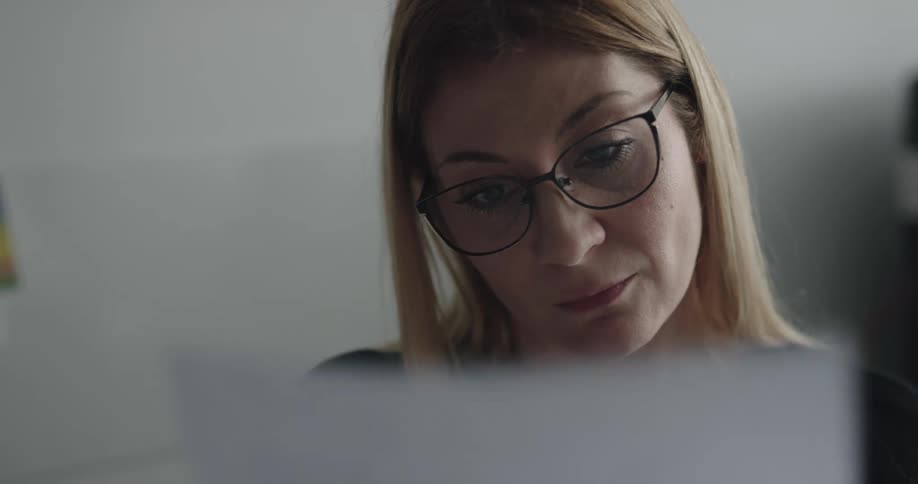 Blonde woman with glasses looks over the documents in the office