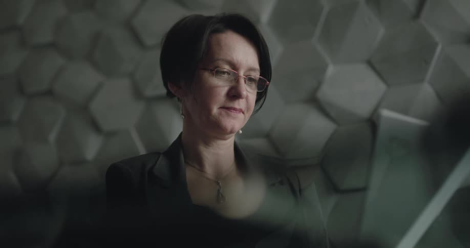 Woman working at the office puts on glasses to work on a computer