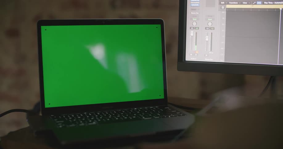 Laptop with green screen and desktop computer on the table