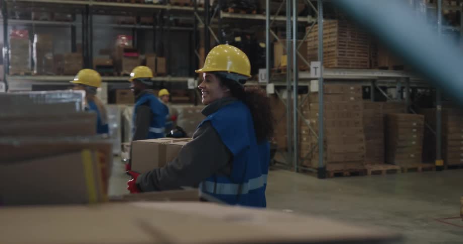 Warehouse workers waving and greeting each other while working