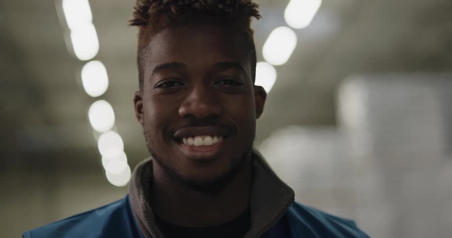 Warehouse worker looks up at the camera and smiles