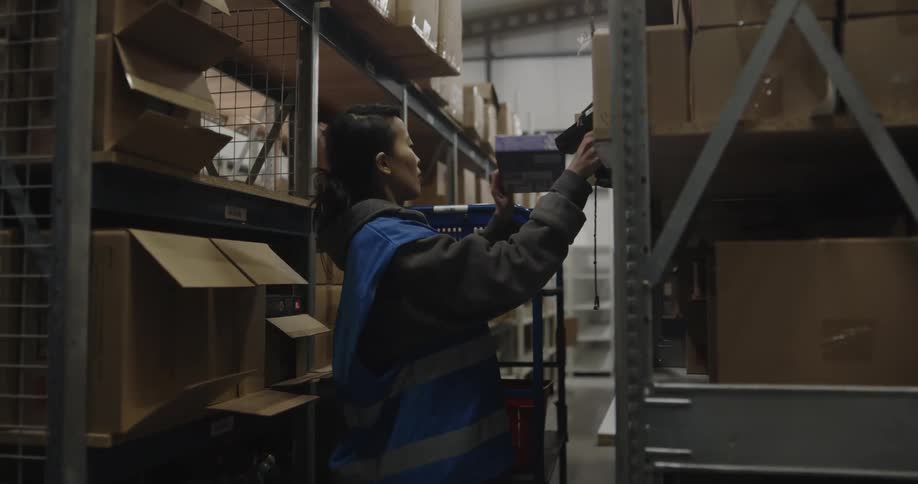 A woman is working in a warehouse and scanning boxes