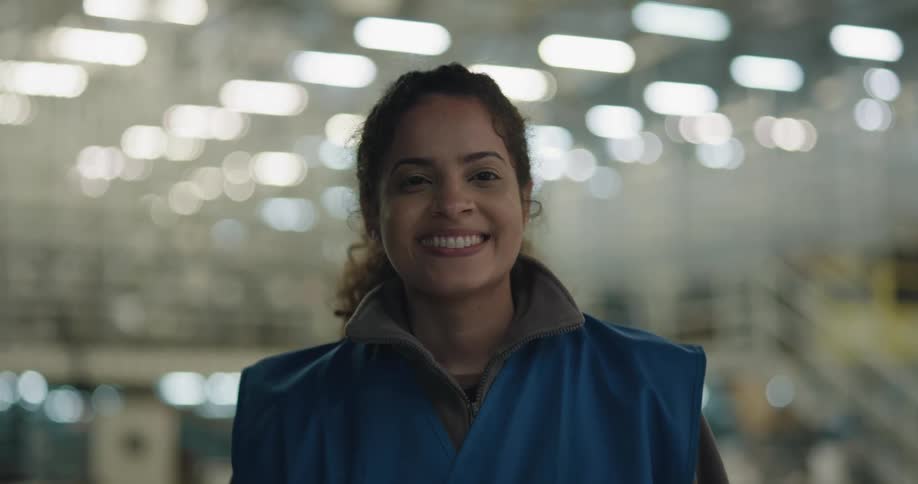 Female employee on a warehouse looks up at the camera and smiles