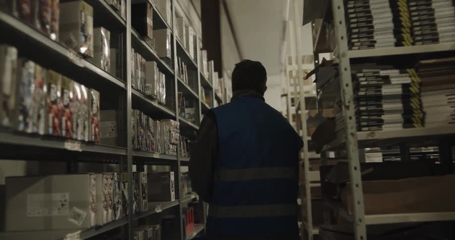 A man carries a basket as he searches warehouse shelves