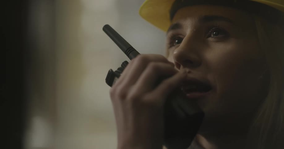 A woman in a hard hat talking on a walkie talkie