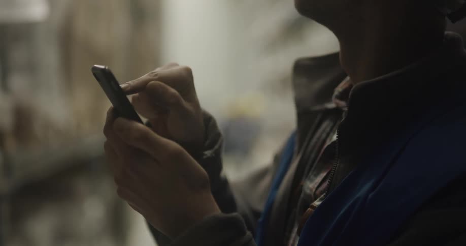A man looking at something on his phone in a warehouse