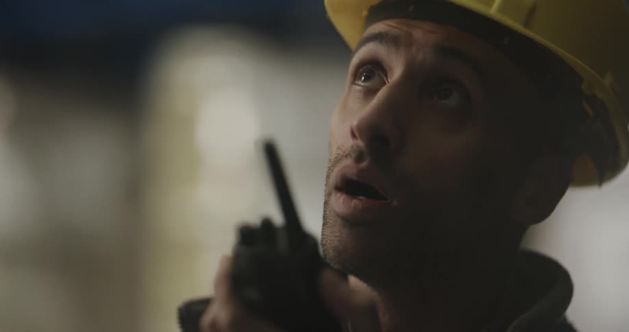 A man that is talking on a walkie talkie with a hard hat on
