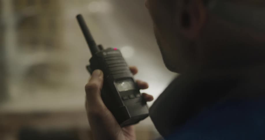 Worker standing in front of stocked shelf communicates via two way radio