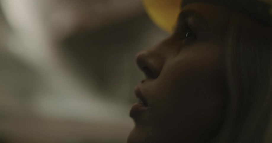 A woman with a hardhat talking on a walkie talkie in a warehouse