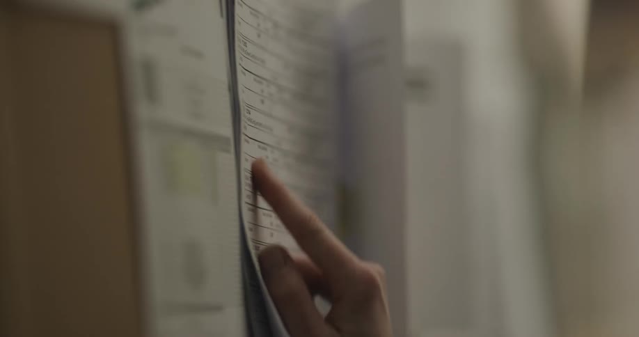 A woman reading a paper on a bulletin board with thumbtacks